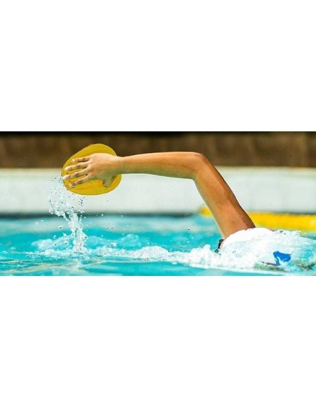 Nuotatore in piscina durante la bracciata a stile libero con paletta gialla sulla mano